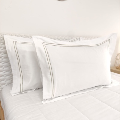 Conjunto de roupas de cama brancas com fronhas com linhas cinza peroladas e edredão acolchoado