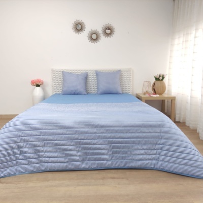 Cama com colcha azul listrada e almofadas azuis num quarto minimalista