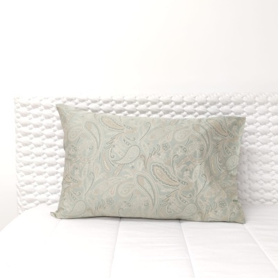 Travesseiro com padrão floral em tons azuis e bege sobre cama branca