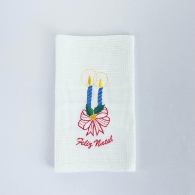 Toalha branca com bordado de velas azuis, laço vermelho e texto Feliz Natal