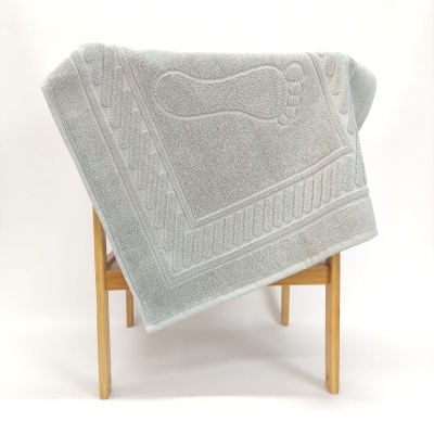 Toalha de banho cinza clara com padrão de pegada sobre estrutura de madeira