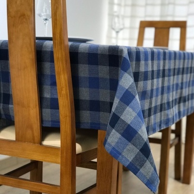 Mesa de madeira com toalha de mesa xadrez azul e cinza e cadeiras de madeira