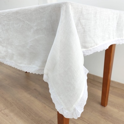 Toalha de mesa branca com bordado em renda em cima de mesa de madeira