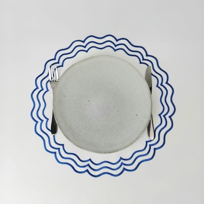 Mesa posta com prato cinzento e lugar americano com linhas azuis onduladas