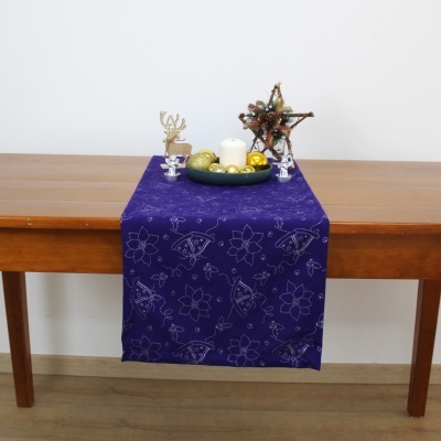 Caminho de mesa roxo com padrão floral e decoração natalícia sobre mesa de madeira