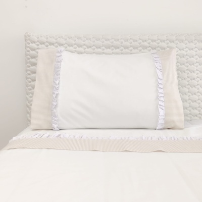 Almofada branca decorativa com bordas bege e franzidas apoiada em cabeceira acolchoada branca