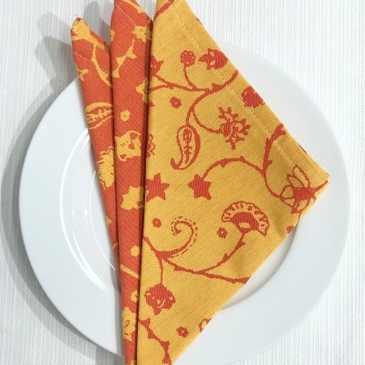 guardanapo de tecido amarelo e laranja com padrão floral num prato branco