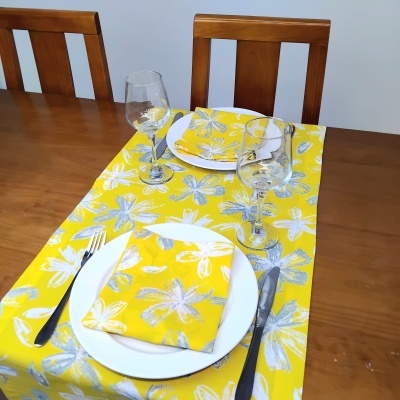 Mesa de jantar com toalha e guardanapos florais amarelos e pratos brancos