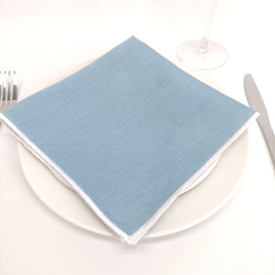 Guardanapo azul dobrado em prato branco com talheres e taça