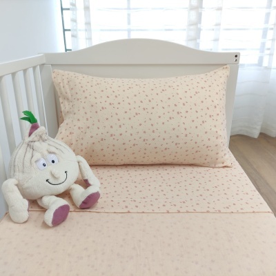 Cama de crianças com lençol bege com pequenas estrelas vermelhas e peluche sorridente