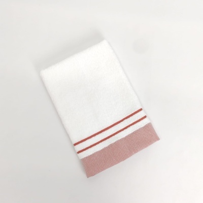 Toalha branca com riscas laranja e borda cor de tijolo