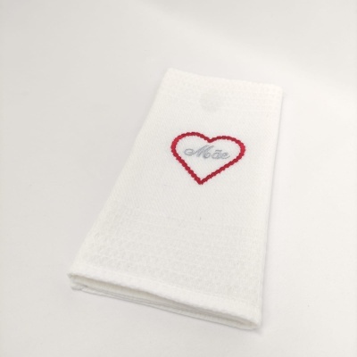 Toalha branca com bordado de coração e palavra 'Mãe'