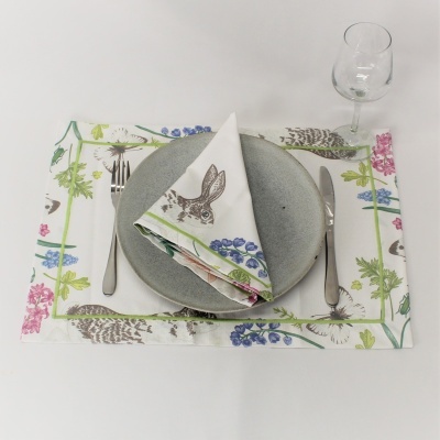 Conjunto de mesa com toalha estampada, prato cinza, talheres e copo