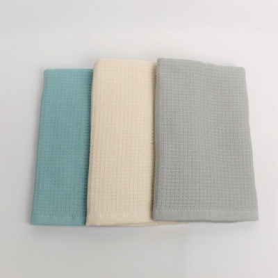 Três toalhas de banho azul claro, creme e cinza claro com padrão texturizado