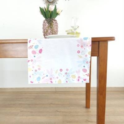Toalha de mesa branca com padrão de Páscoa pendurada numa mesa de madeira clara