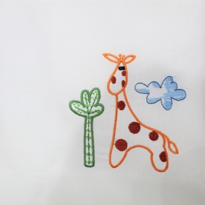 Almofada branca com bordado de girafa, árvore e nuvem