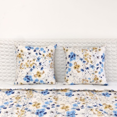 Almofadas e edredão com padrão floral azul e amarelo sobre fundo branco