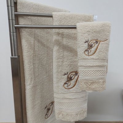 Conjunto de toalhas bege com bordado dourado penduradas em suporte metálico