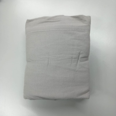 Peça de vestuário bege claro dobrada sobre mesa branca