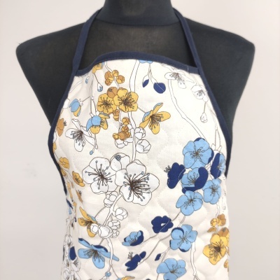 Avental de cozinha floral azul e amarelo em manequim preta