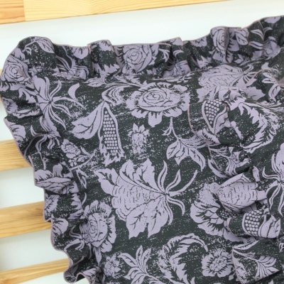 Peça de roupa preta com padrão floral lilás e detalhe franzido em madeira clara