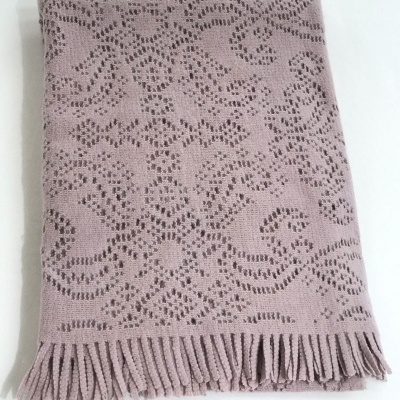 Cobertor rosa claro com padrão de flores e franjas.