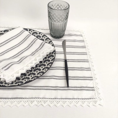 Conjunto de jantar com prato azul, guardanapo e toalhete riscado branco e cinza, copo cinza e faca preta.