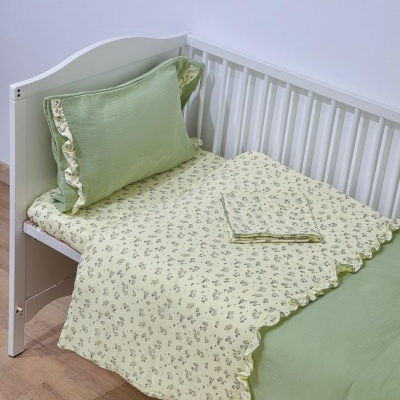 Cama de criança branca com roupa de cama verde e amarela com padrão floral
