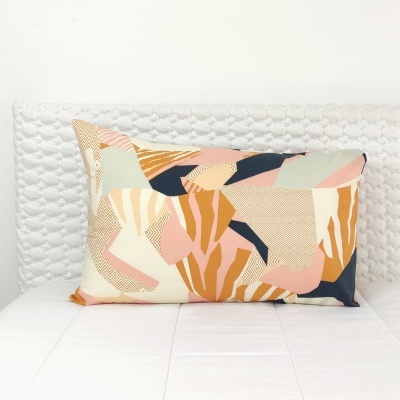 Almofada retangular colorida com padrão abstrato sobre cama branca acolchoada