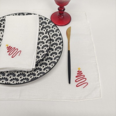 Jogo de jantar com pratos brancos e pretos, guardanapo e toalha com bordado de árvore de Natal, taça vermelho e faca preta e dourada