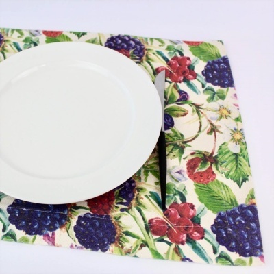 Prato branco sobre guardanapo com padrão de frutas e faca ao lado