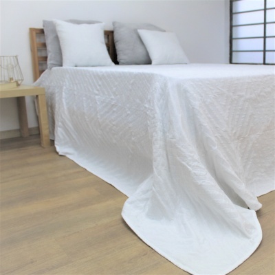 Cama com colcha branca texturizada e almofadas brancas e cinza em quarto minimalista