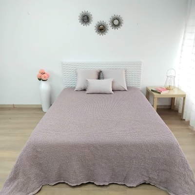 Cama de casal com colcha cinzenta, almofadas, cabeceira branca e decoração minimalista