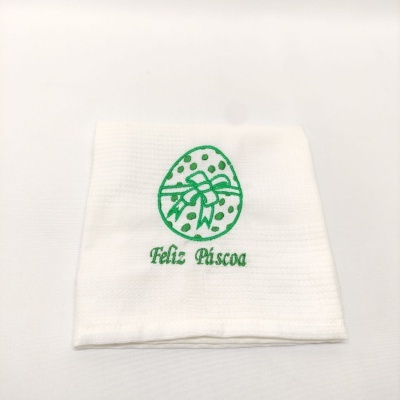 Guardanapo branco com bordado verde de ovo de Páscoa e texto Feliz Páscoa