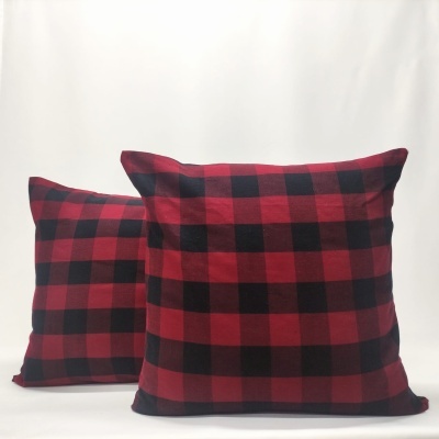 Duas almofadas com padrão xadrez preto e vermelho em fundo branco