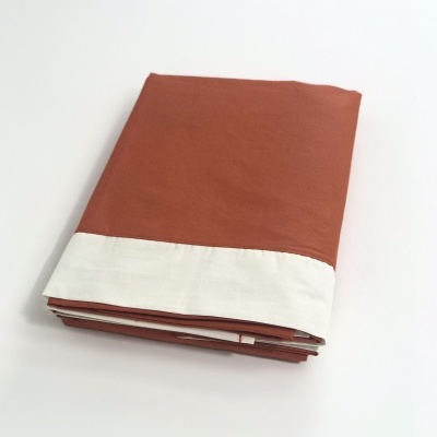 Lençol castanho e branco dobrado sobre uma superfície branca