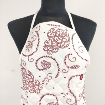 Avental branco com padrão decorativo vermelho em manequim negro