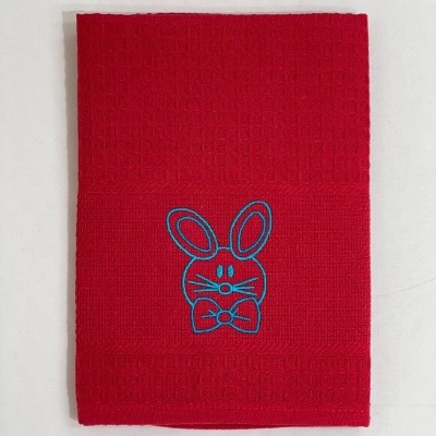 Toalha vermelha com bordado azul de coelho, vista de cima.