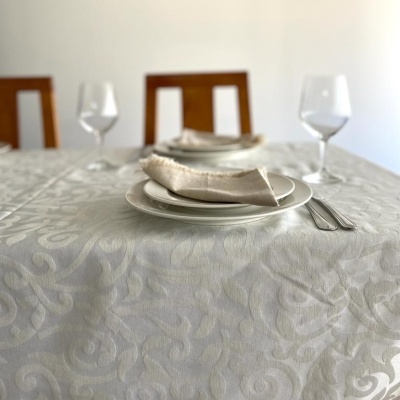 Mesa posta com toalha branca e pratos brancos, guardanapo bege e taças de vidro