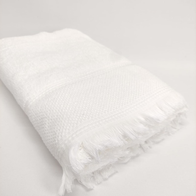 Toalha branca dobrada com franja nas extremidades
