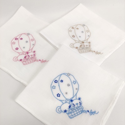 Três panos de tecido branco com bordados de balões de ar quente e ursinhos em rosa, castanho e azul