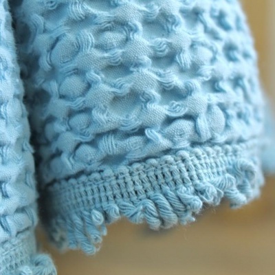 Toalha azul clara com textura de bolhas e franjas