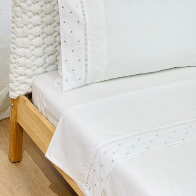 roupa de cama branca com padrão de estrelas verdes e bordado