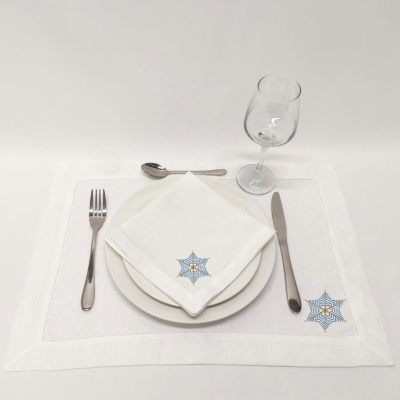 Mesa posta com jogo americano e guardanapo branco com padrão colorido, talheres e copo de vinho.