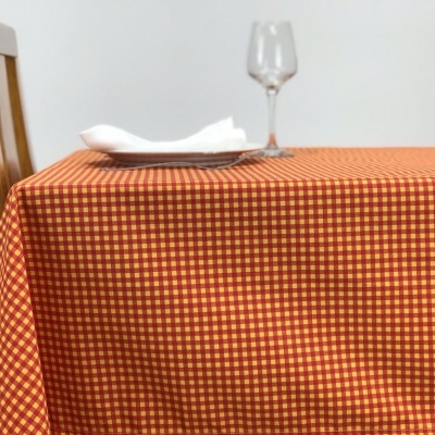 Toalha de mesa xadrez laranja com guardanapo branco e copo de vidro sobre a mesa