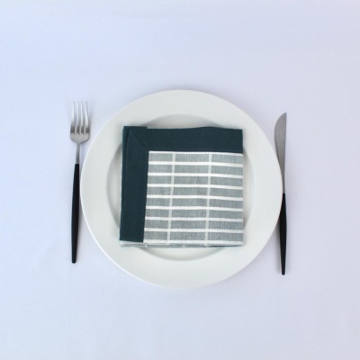 Talheres com prato branco e guardanapo cinza e azul numa mesa branca