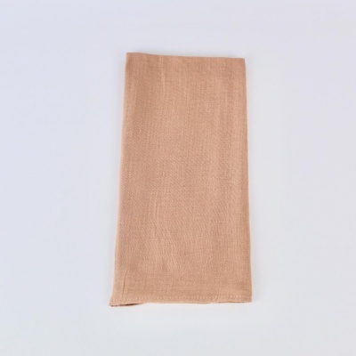 Guardanapo de tecido bege claro dobrado sobre fundo branco