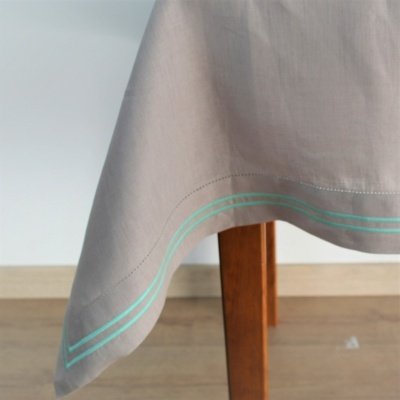 Toalha de mesa bege com linhas azuis nas bordas sobre perna de mesa de madeira