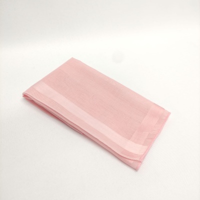 Guardanapo de tecido cor-de-rosa com faixas claras dobrado sobre fundo branco