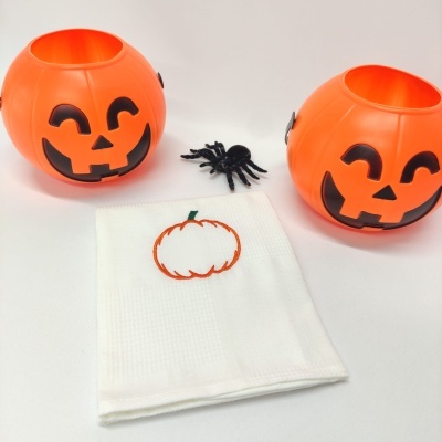 Dois recipientes de abóboras de Halloween e pano branco com bordado de abóbora
